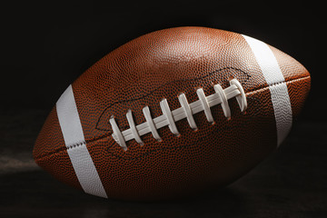 New American football ball on table against dark background