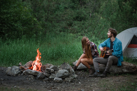 Couple snuggling by campfire