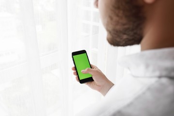 Close-up of male hands using smartphone near the window. Close u