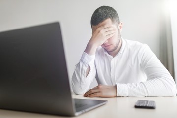 Young smiling bearded businessman is working on computer holding