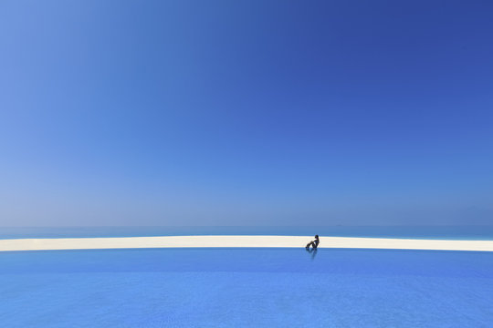 A young woman sitting on a pools edge