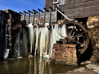 Long icicles hang from the flume and waterwheel of the old gristmill or watermill at Historic Yates Mill County Park in Raleigh North Carolina