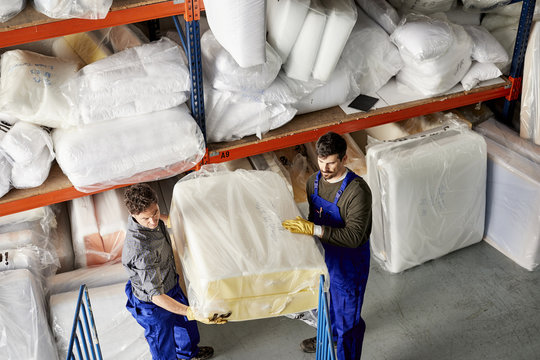 Workers Carrying Mattress Package In Warehouse At Sofa Workshop