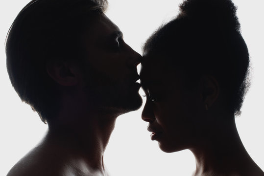 Side View Of Silhouettes Of Interracial Couple In Love