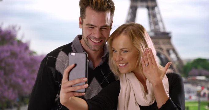 Joyful engaged couple taking a selfie in Paris, Loving man and woman take a picture near the Eiffel Tower to share news with friends, 4k