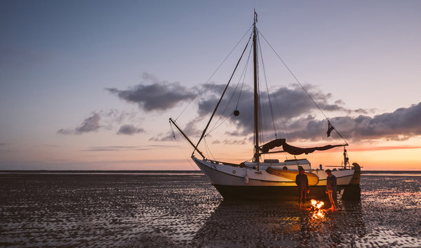 Two friends stay warm during there adventure  after they got stuck with their sailboat on a sandbank when being surprised by low tide