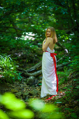 Portrait of romantic blonde woman in white dress in fairy forest, selective focus. concept of fabulous nymph