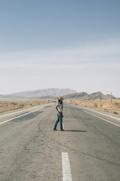 beautiful woman standing on a road in the desert