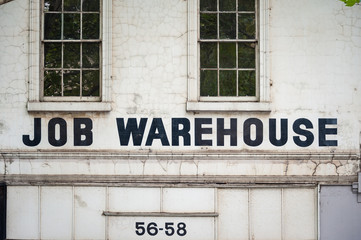 Job warehouse sign on white wall of an old, unused building