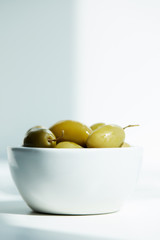 bowl with green olives on white table