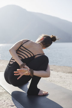Woman doing Twisting Garland Pose, Bada Malasana