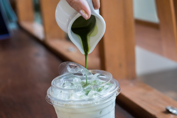 Pouring the green tea into the milk, make a cup of Matcha latte.