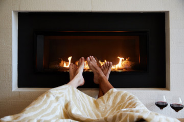 Couple relaxing in front of fireplace with wine