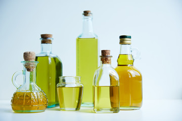 different bottles of aromatic olive oil and jar on white background