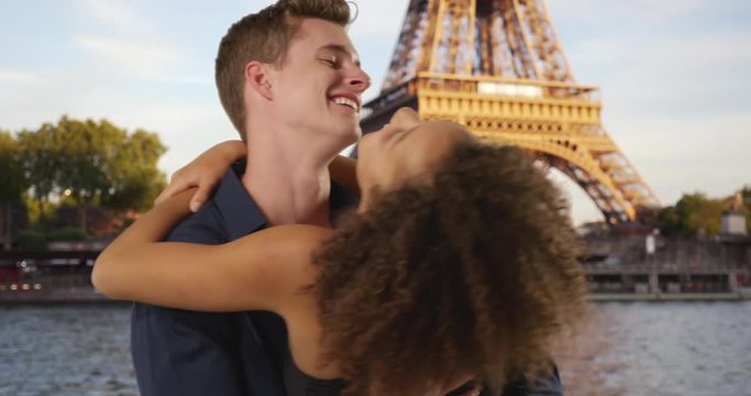 Happy couple hugging in front of the Eiffel Tower, Caucasian male and African female enjoy dream vacation in Paris, 4k