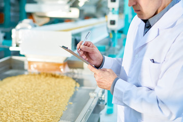 Mid section portrait  of  unrecognizable factory worker doing  production quality inspection in...