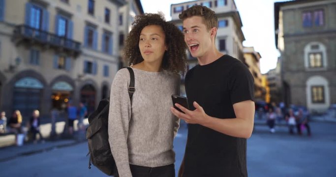 Portrait of two millennial tourists using map on smartphone in Florence, Multiethnic male and female use cellphone for directions on Florence street, 4k