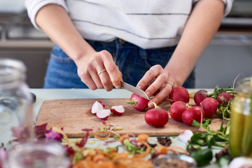 Woman cutting fresh vegetables on wooden chopping board