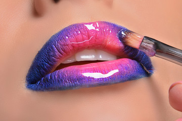 colorful woman lips, makeup artist applies lip gloss whith cosmetic brush