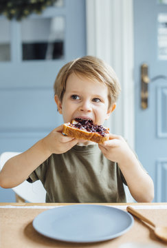 Young boy eating toast with jam for breakfast