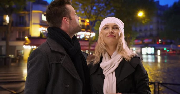 Loving couple exploring Paris streets at night, Man and woman tourists looking around smiling in evening, 4k