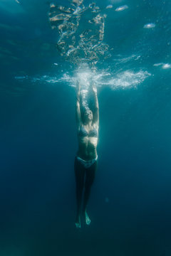 Wide shot of a woman swimming underwater