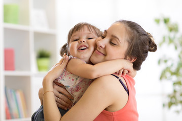 love and family concept - happy mother and child daughter hugging at home