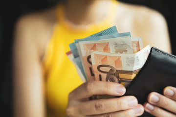 A female hand piking up or counting money in the wallet.