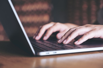 Closeup image of hands working and typing on laptop keyboard in office