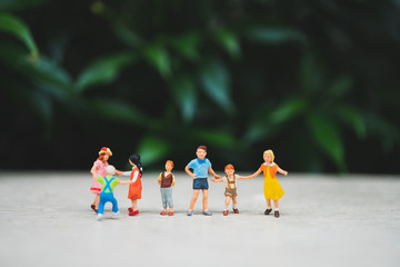 Miniature people, group of children playing on green nature background using as family and education concept - Vintage filter