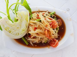 Thai food style, Papaya salad with tomato, shrimp, chili, bean, morning glory and cabbage on white plate. isolated on white background, Space for text in template, healthy food concept.