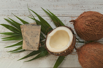 Fototapeta na wymiar coconut soap.soap with coconut extract. Handmade soap with coconut oil on a palm leaf and fresh coconut in a cut on a shabby wooden background. Organic Natural Cosmetics