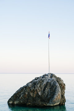 Rock with a flag in the sea