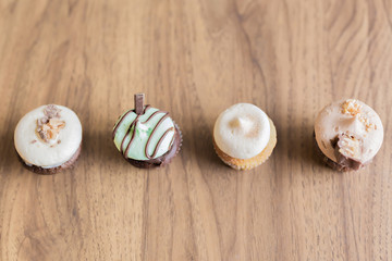 A variety of cupcakes lined up on a wooden table 
