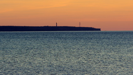 Latarnia morska świecąca po zmroku na estońskim klifie wystającym na morzu bałtyckim