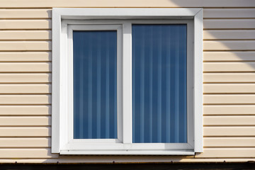 Window of a private house on a background of beige siding.