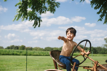 Little kid on old tractor at farm