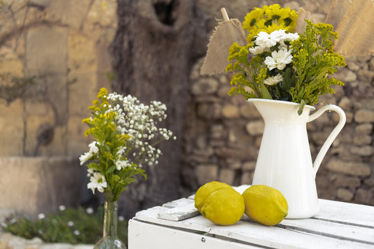 Yellow lemons with white jar lemon juice with plants decoration