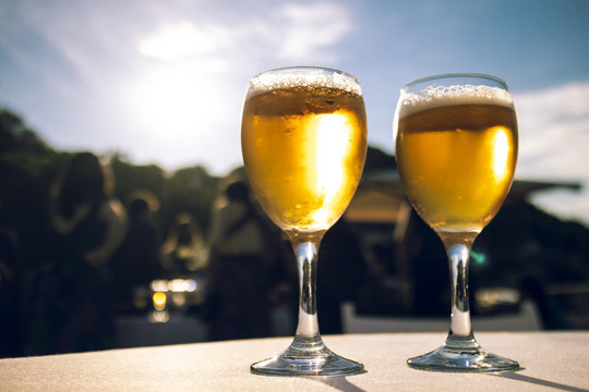 Two bright blond beers close up on an outdoor summer party