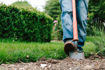 Man using a small shovel to dig a flower bed