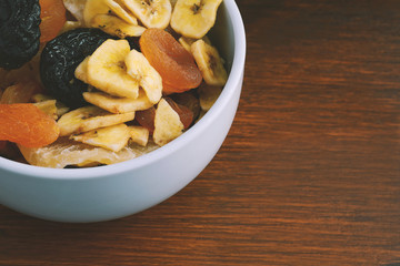 Close up bowl with different dried fruits on wooden background