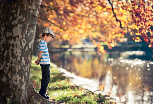 Boy in a park beside a lake in autumn with fall colors