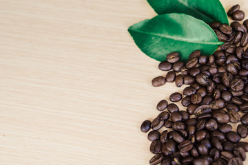 Cup of coffee on coffee beans and leaf on the wooden table with copy space. 