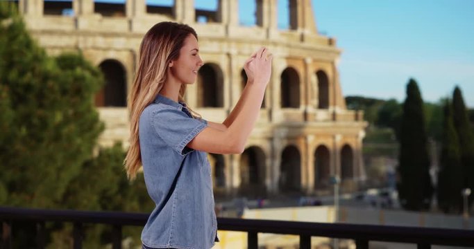 Smiling tourist recording video of summer vacation in Rome, Happy attractive female near the Coliseum takes picture with her cellphone, 4k