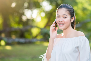 Asian Young happy woman talking on cell phone  in summer park.