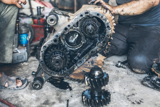 totally destroyed transfer gear box inspected by dirty and oily mechanics