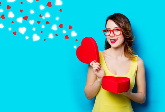 portrait of beautiful young woman with heart shaped gift on the wonderful blue studio background and abstract hearts