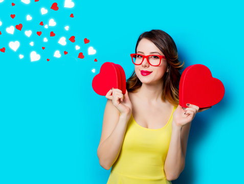 portrait of beautiful young woman with heart shaped gifts on the wonderful blue studio background and abstract hearts