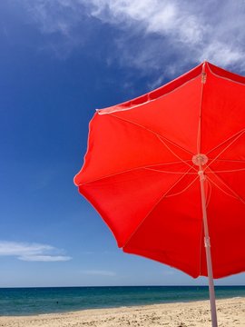 Red umbrella on a beach over blue sky