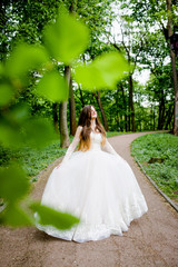 A refined woman in a white dress poses in the park